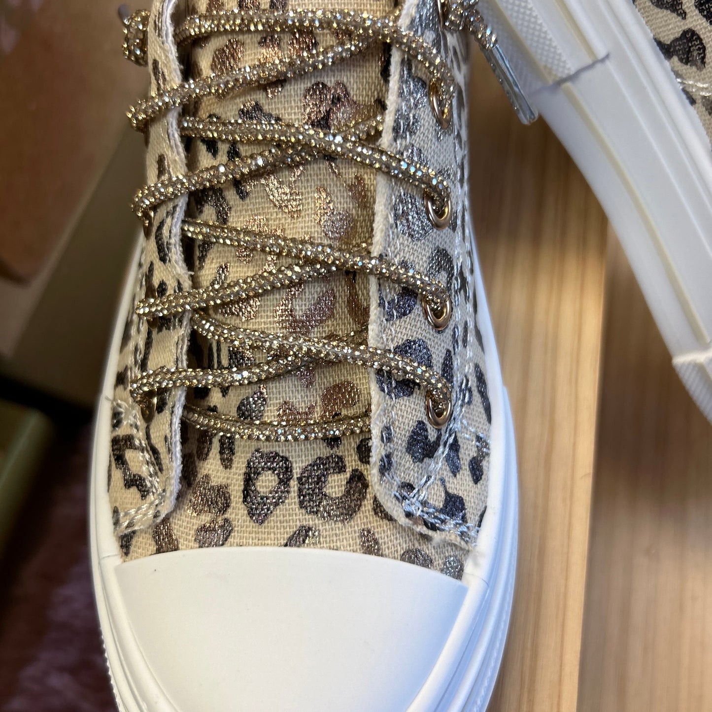 Leopard print sneaker with decorative laces on a wooden surface