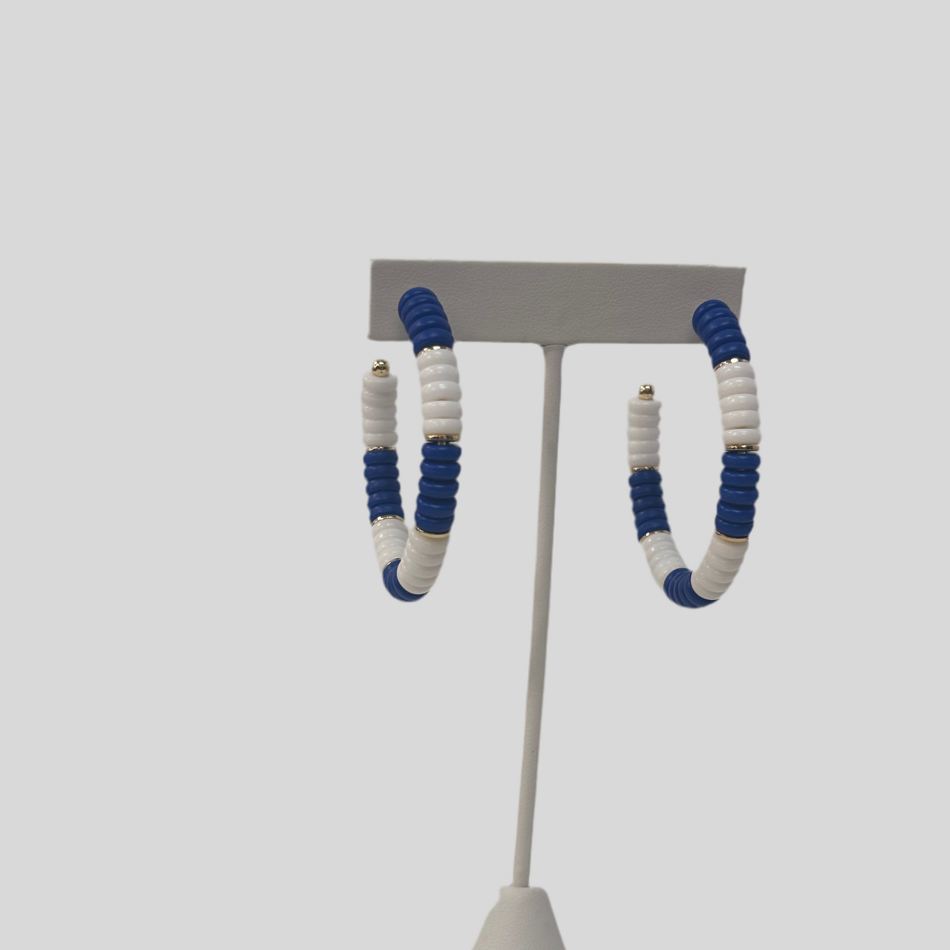 Pair of earrings on a gray stand against a white background